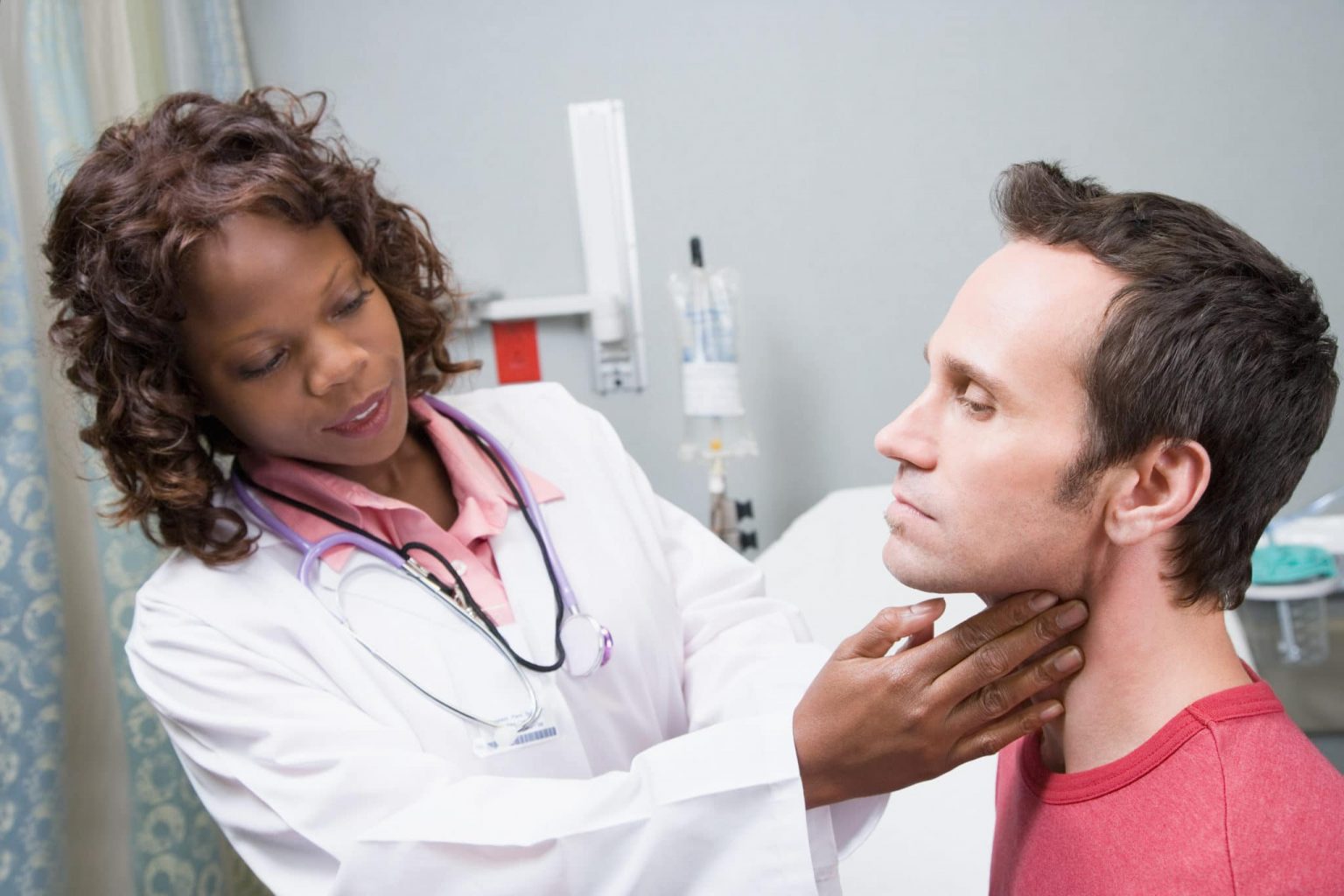 head-and-neck-cancer-evaluation Female doctor examines the outside of a male patient's throat.